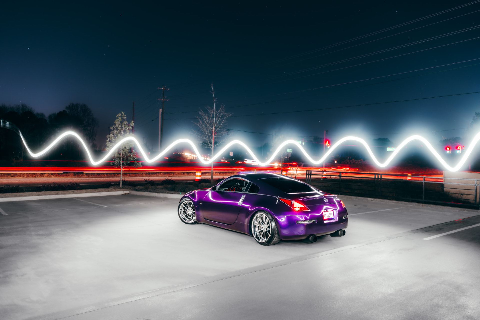 Purple Nissan 350Z light-painted at night with a white light trail along a road