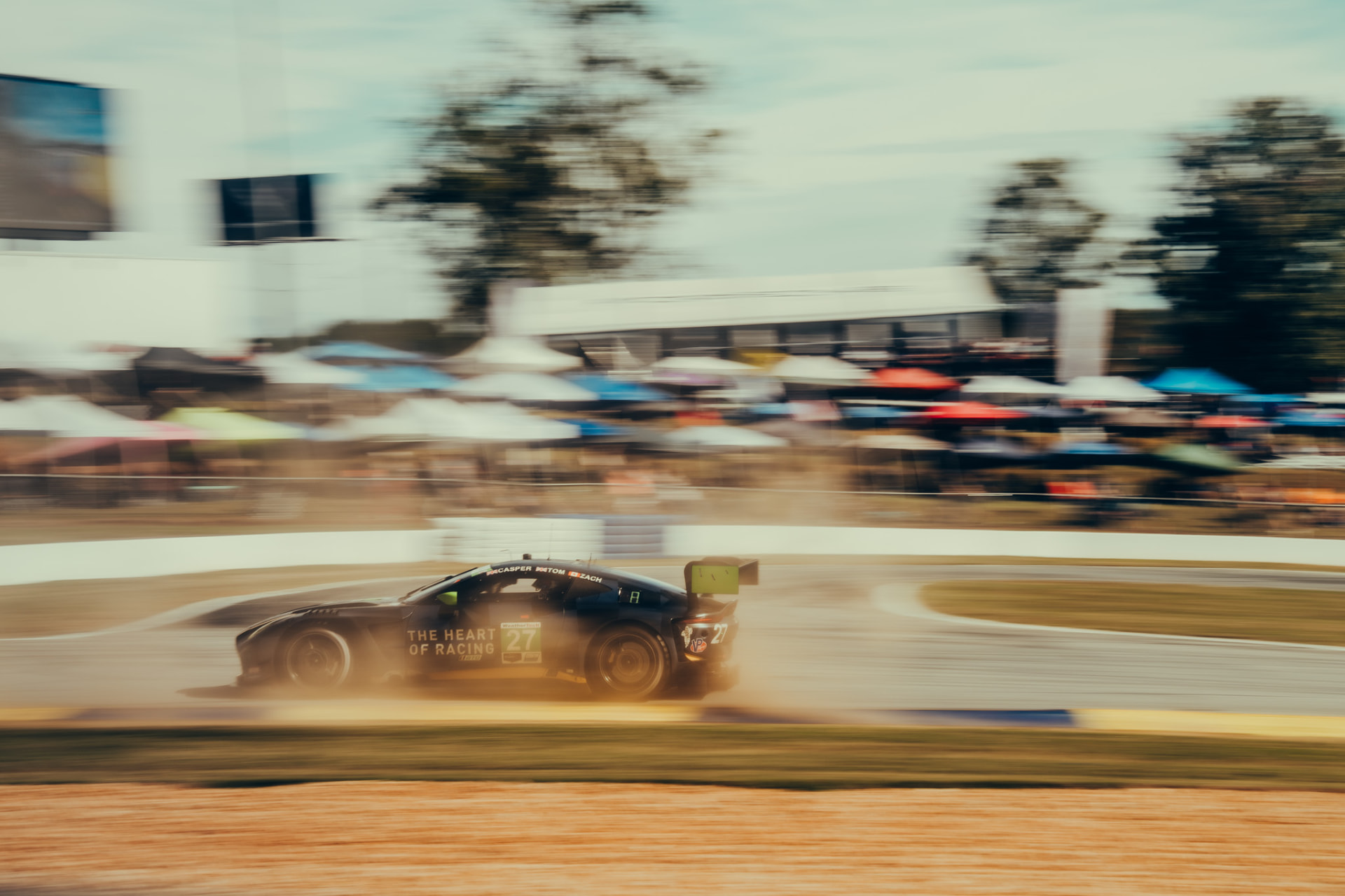 Aston Martin Vantage GT3 race car drifting through a corner with dust behind it